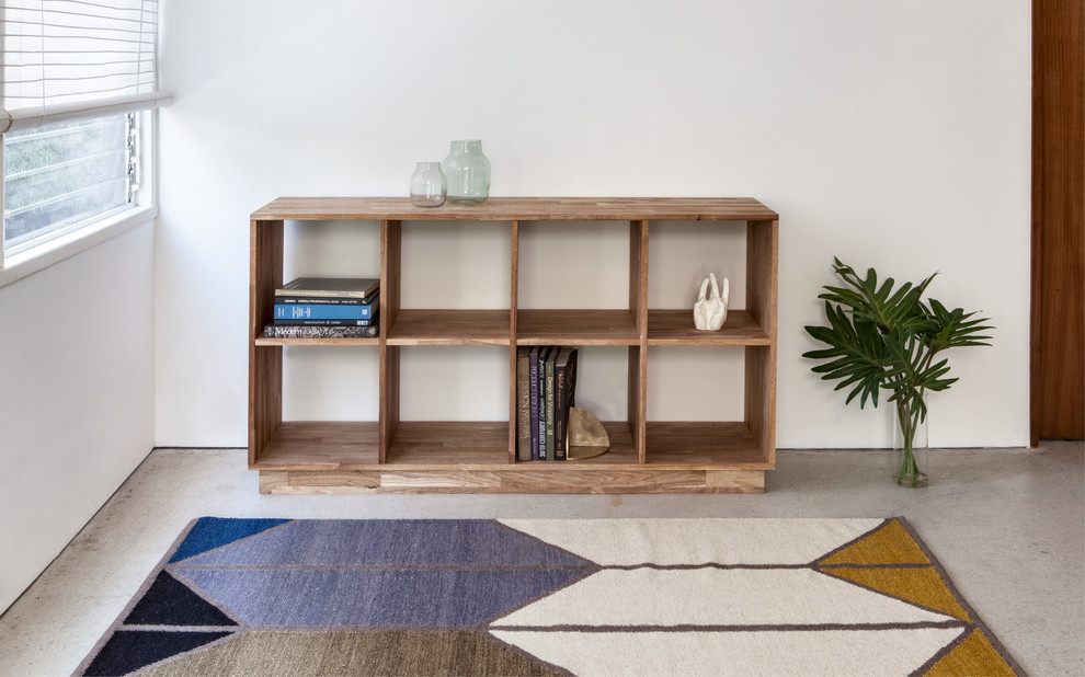 Immagine di un piccolo soggiorno shabby-chic style chiuso con libreria, pareti bianche, pavimento in cemento e nessuna TV