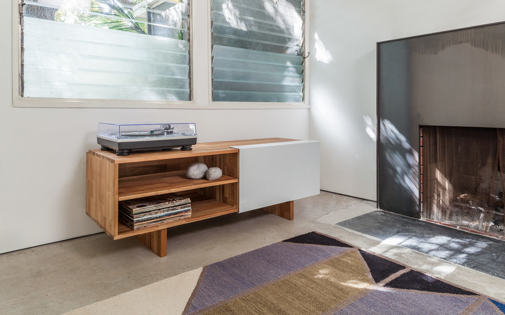 Mittelgroßes, Fernseherloses, Abgetrenntes Modernes Musikzimmer mit weißer Wandfarbe, Betonboden, Kamin und Kaminumrandung aus Metall in Los Angeles