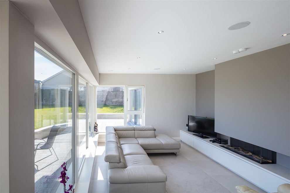 Cette image montre un grand salon design ouvert avec un mur gris, un sol en carrelage de porcelaine, cheminée suspendue, un manteau de cheminée en plâtre, un téléviseur indépendant et un sol beige.