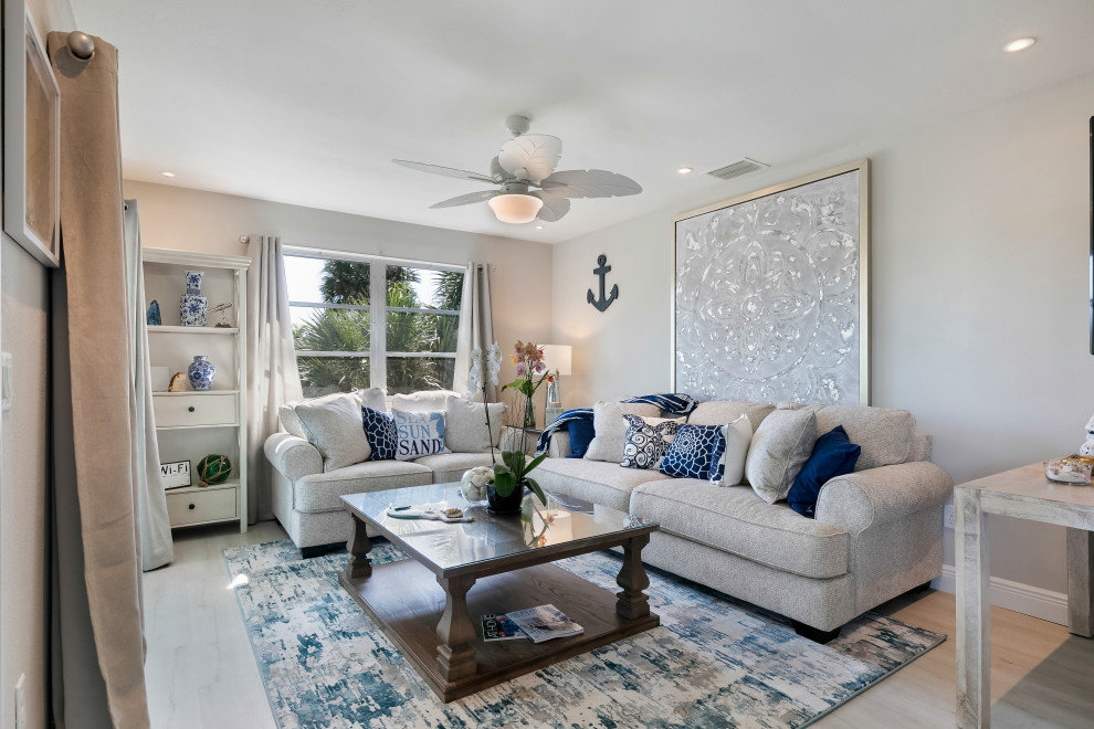 Kleines, Offenes Maritimes Wohnzimmer ohne Kamin mit weißer Wandfarbe, hellem Holzboden, TV-Wand und beigem Boden in Miami