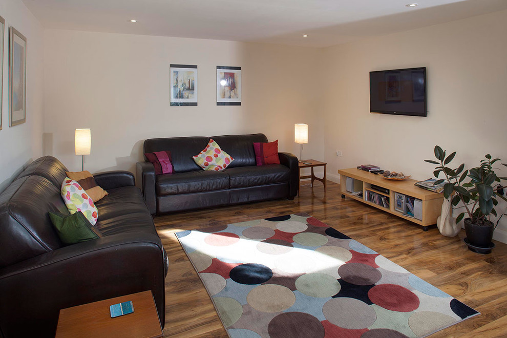 Immagine di un piccolo soggiorno design aperto con pareti bianche, parquet chiaro, stufa a legna, cornice del camino piastrellata e TV a parete