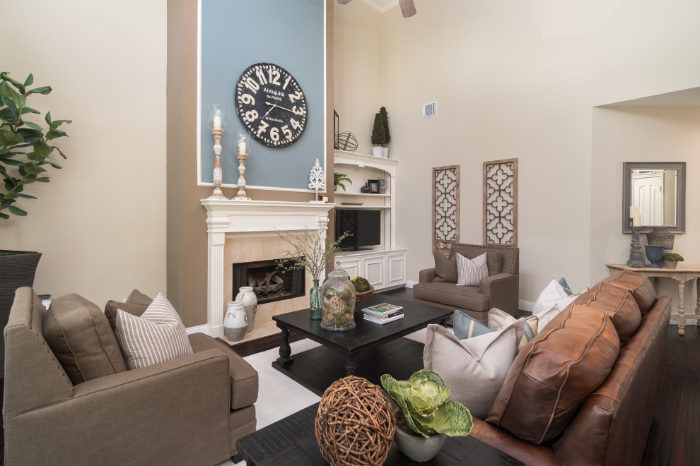 Cette photo montre un grand salon chic avec une salle de réception, un mur beige, une cheminée standard, un manteau de cheminée en carrelage, un téléviseur encastré et un sol marron.