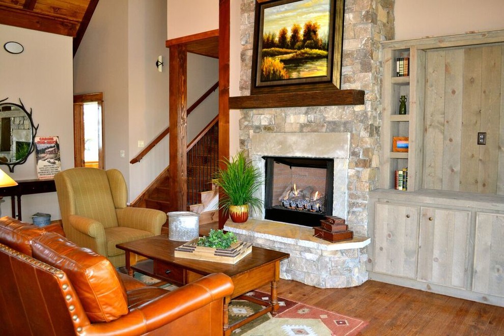 Источник вдохновения для домашнего уюта: гостиная комната в стиле рустика с паркетным полом среднего тона, стандартным камином и фасадом камина из камня