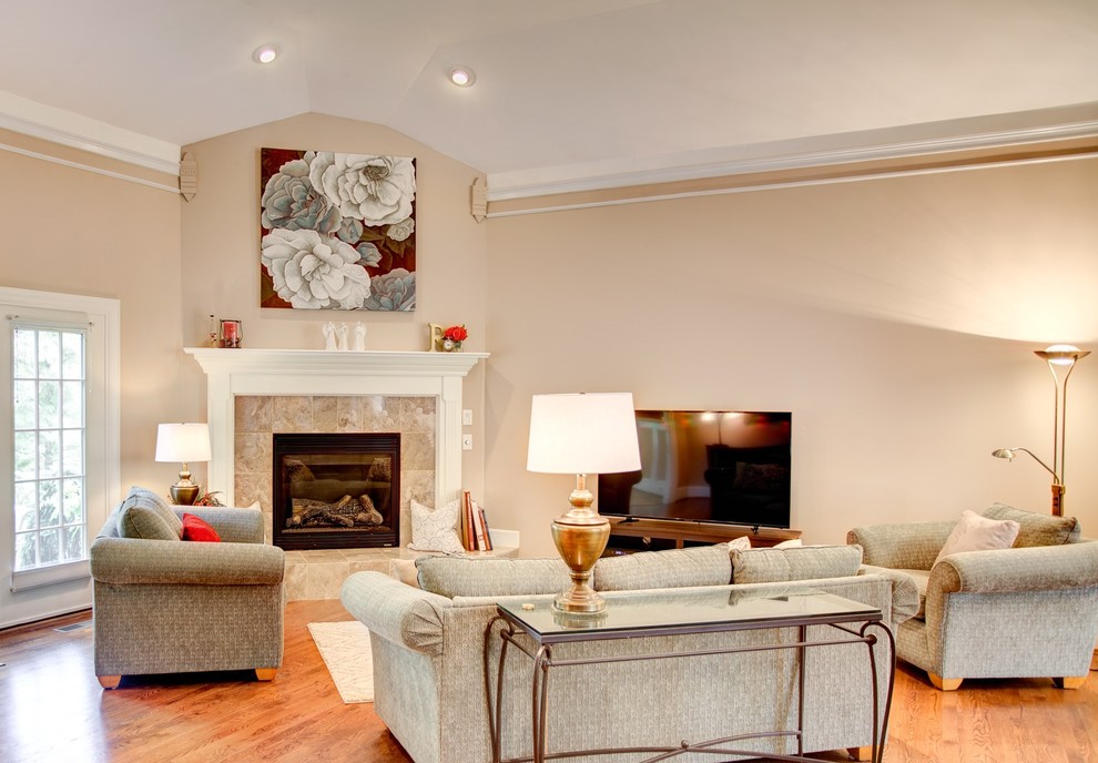 Mittelgroßes, Offenes Klassisches Wohnzimmer mit beiger Wandfarbe, braunem Holzboden, Eckkamin, gefliester Kaminumrandung, freistehendem TV und braunem Boden in Cincinnati