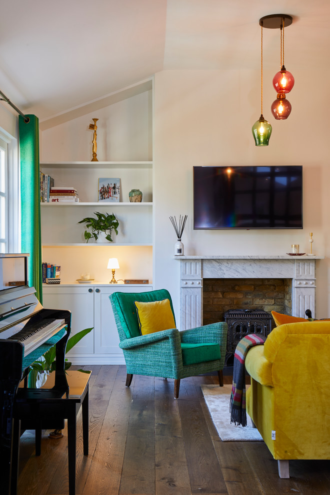 Idee per un soggiorno boho chic con pareti bianche, pavimento in legno massello medio, camino classico, TV a parete e pavimento marrone