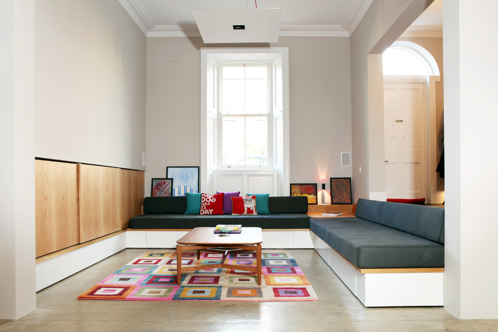 Cette photo montre un grand salon tendance ouvert avec une bibliothèque ou un coin lecture, un mur beige, sol en béton ciré et un téléviseur encastré.