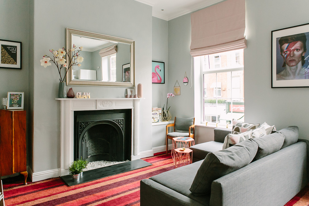 Cette image montre un salon design de taille moyenne et fermé avec un mur gris, moquette, une cheminée standard, un manteau de cheminée en plâtre et un sol rouge.