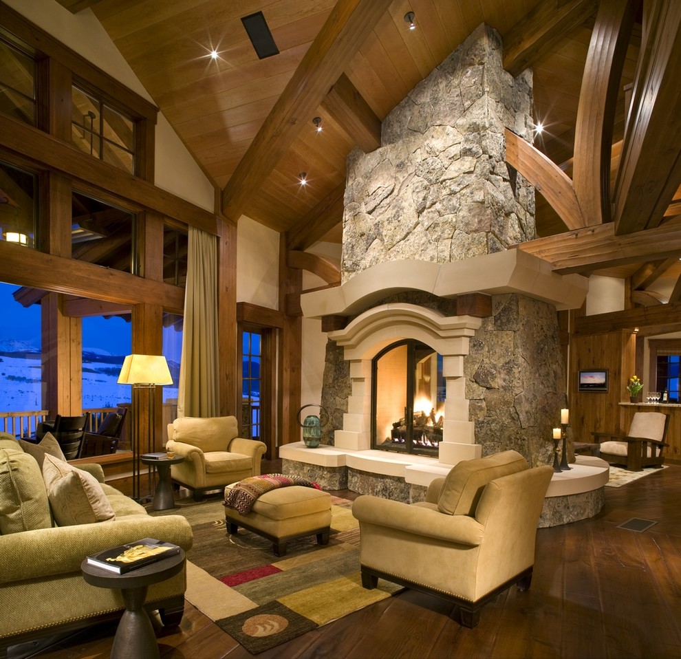 Living room - rustic dark wood floor living room idea in Denver with beige walls, a two-sided fireplace and a stone fireplace