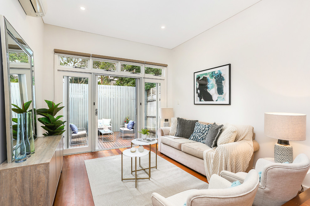 This is an example of a small coastal formal open plan living room in Sydney with medium hardwood flooring, brown floors, white walls, no fireplace and no tv.