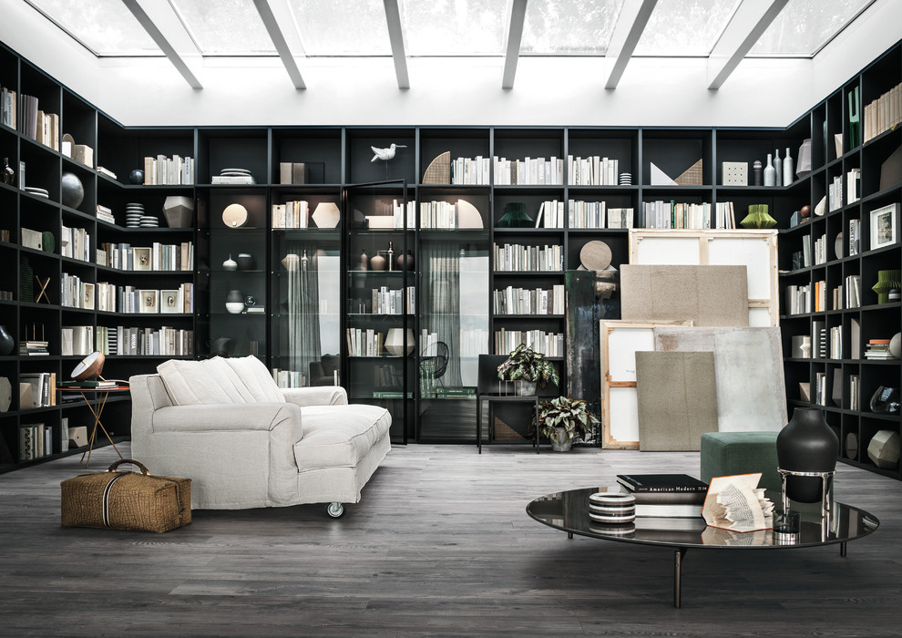 Cette image montre un grand salon minimaliste fermé avec une bibliothèque ou un coin lecture, un mur noir, parquet foncé, aucune cheminée, aucun téléviseur et un sol marron.