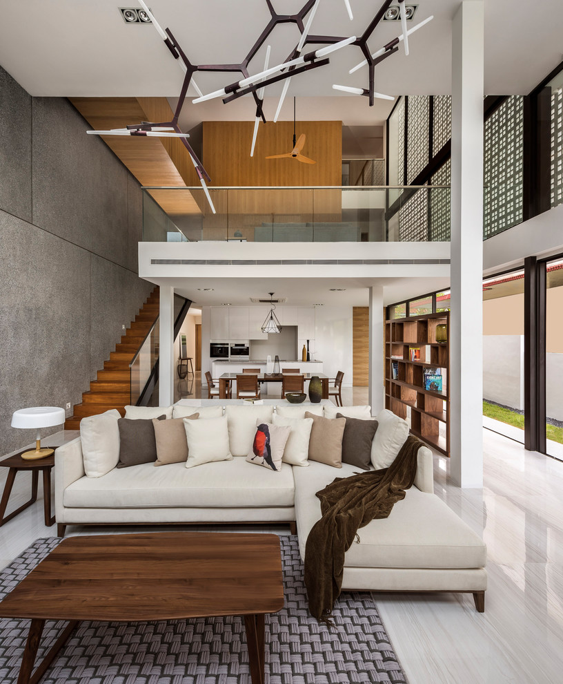 Cette image montre un salon design ouvert avec un mur gris, aucun téléviseur et un sol beige.