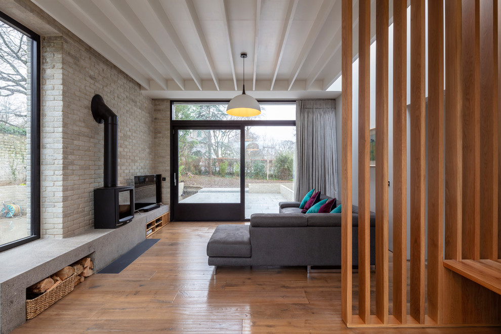 Inspiration för ett funkis vardagsrum, med vita väggar, mellanmörkt trägolv, en öppen vedspis och brunt golv