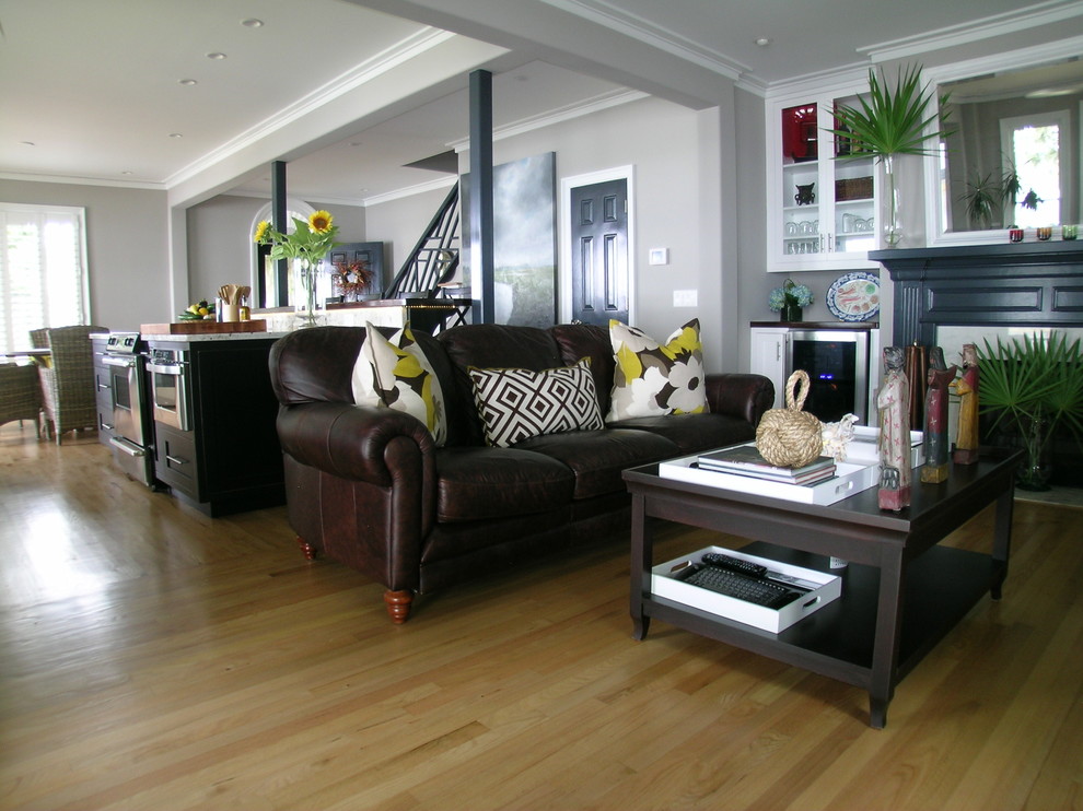 Mittelgroßes, Offenes Eklektisches Wohnzimmer mit grauer Wandfarbe, hellem Holzboden, Kamin und Kaminumrandung aus Holz in Charleston