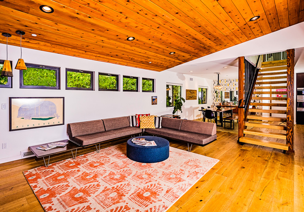 Imagen de salón abierto vintage grande sin chimenea y televisor con paredes blancas, suelo de madera clara y suelo beige