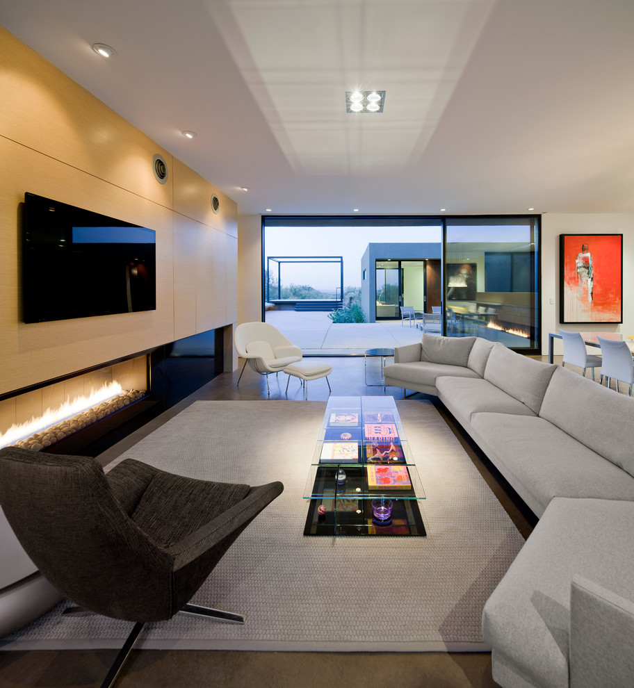 Стильный дизайн: открытая гостиная комната в стиле модернизм с белыми стенами, горизонтальным камином, бетонным полом и телевизором на стене - последний тренд