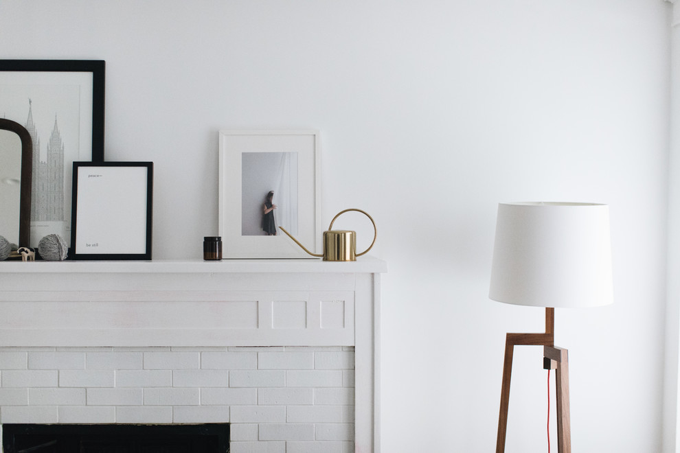 Bild på ett mellanstort minimalistiskt allrum med öppen planlösning, med vita väggar, mellanmörkt trägolv, en standard öppen spis och en spiselkrans i tegelsten