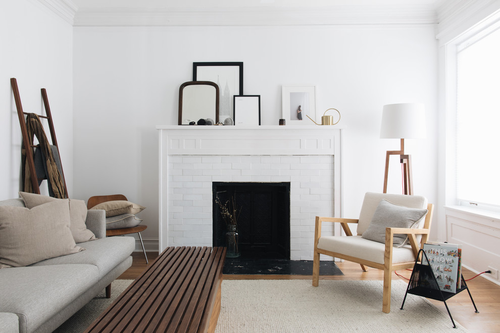 Стильный дизайн: гостиная комната среднего размера в скандинавском стиле с белыми стенами, стандартным камином, светлым паркетным полом и ковром на полу - последний тренд
