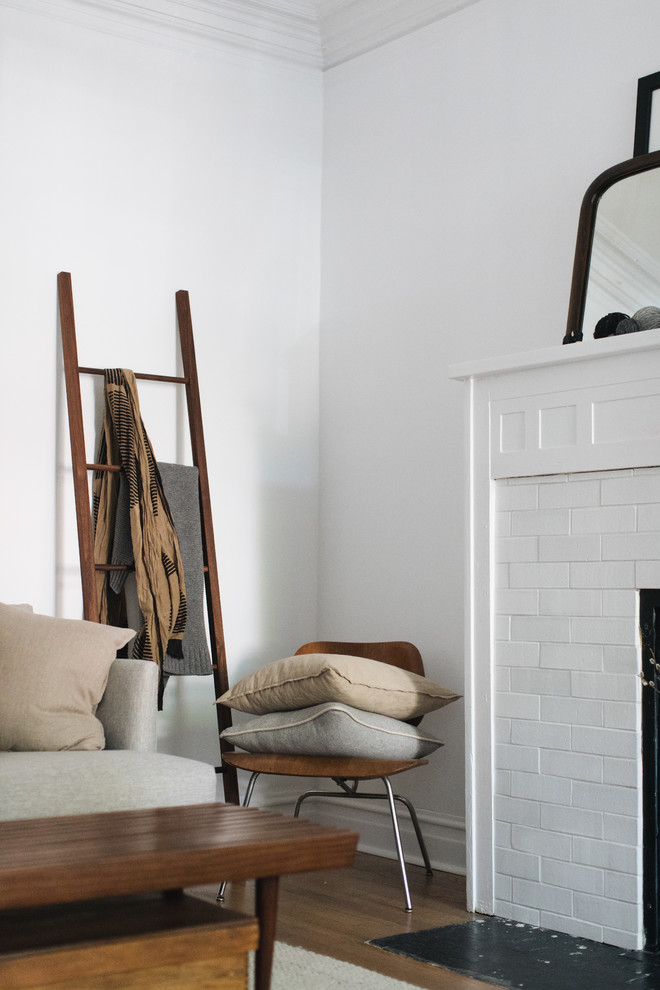 シカゴにある低価格の中くらいな北欧スタイルのおしゃれなLDK (白い壁、無垢フローリング、標準型暖炉、レンガの暖炉まわり) の写真