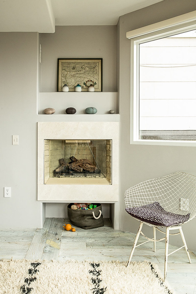 Exempel på ett minimalistiskt vardagsrum, med grå väggar, ljust trägolv och en standard öppen spis