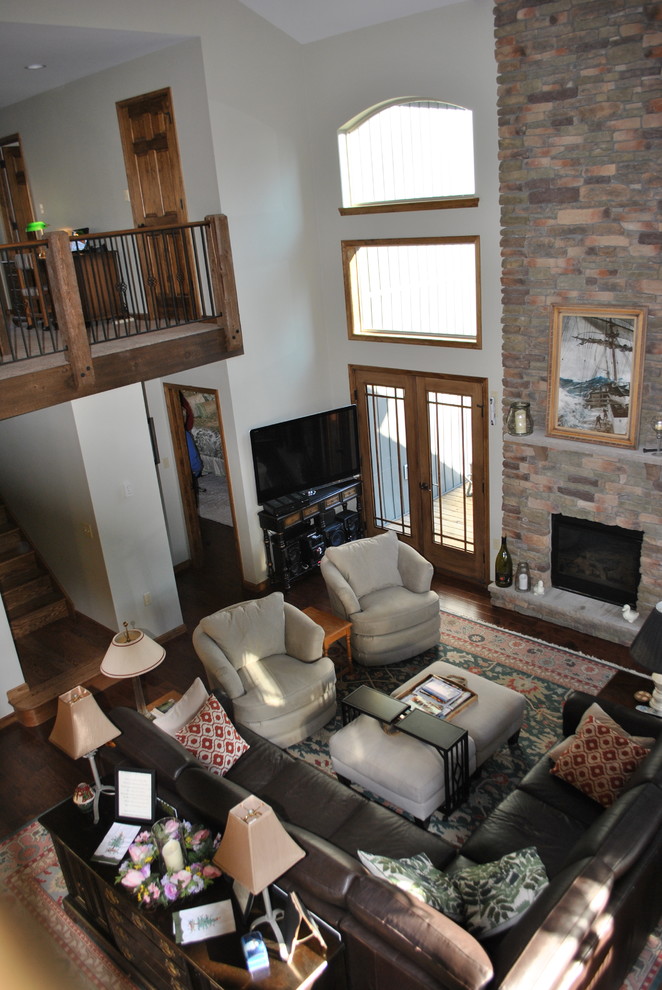 This is an example of a large rustic open plan living room in Other with beige walls, slate flooring, a standard fireplace, a stone fireplace surround and black floors.