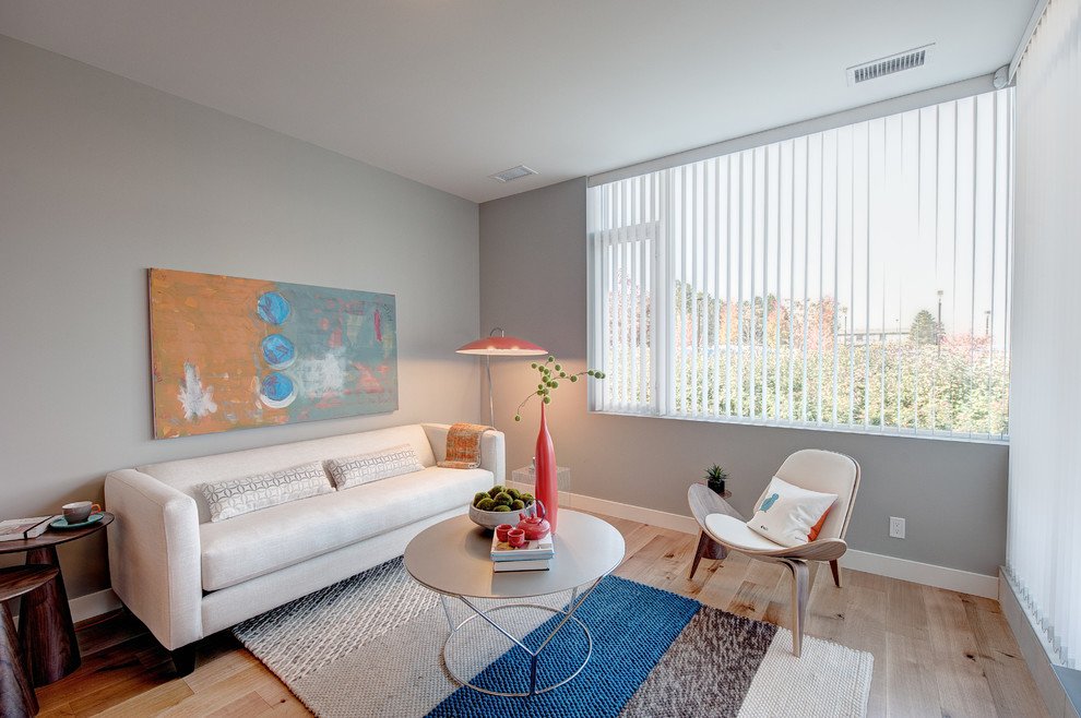 Kleines, Offenes Modernes Wohnzimmer ohne Kamin mit grauer Wandfarbe, hellem Holzboden und TV-Wand in Vancouver