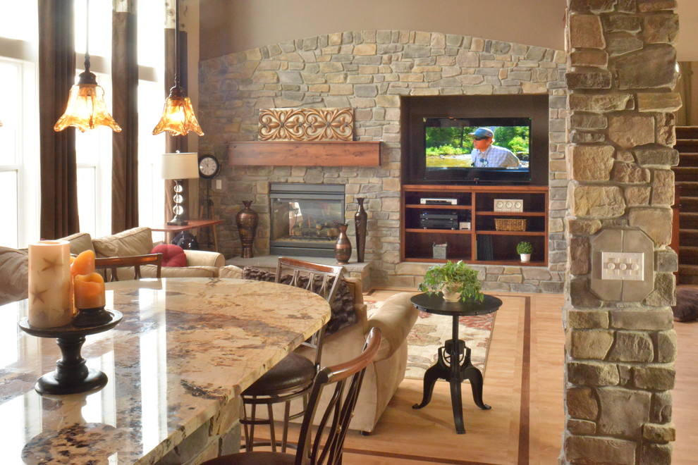 Immagine di un grande soggiorno classico aperto con pareti grigie, parquet chiaro, camino classico, cornice del camino in pietra e parete attrezzata