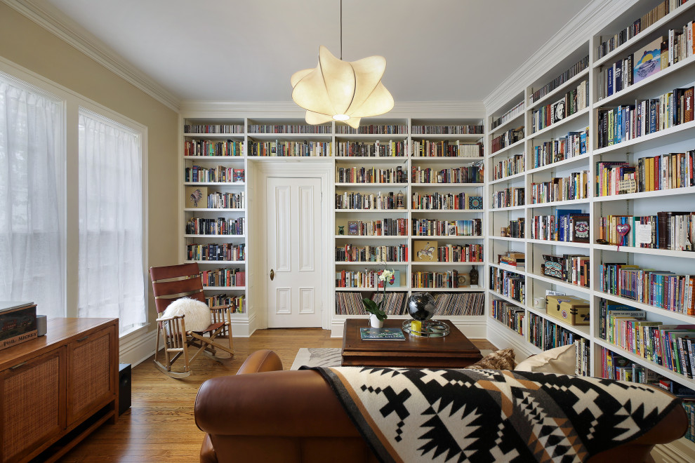 Idee per un soggiorno chic chiuso con libreria, pareti beige, pavimento in legno massello medio e pavimento marrone