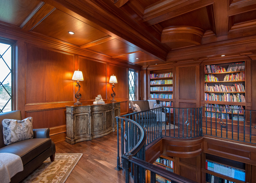 На фото: огромная гостиная комната в классическом стиле с с книжными шкафами и полками, коричневыми стенами и паркетным полом среднего тона с