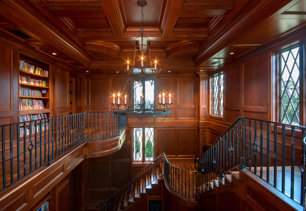 Ejemplo de biblioteca en casa abierta clásica extra grande con paredes marrones y suelo de madera en tonos medios