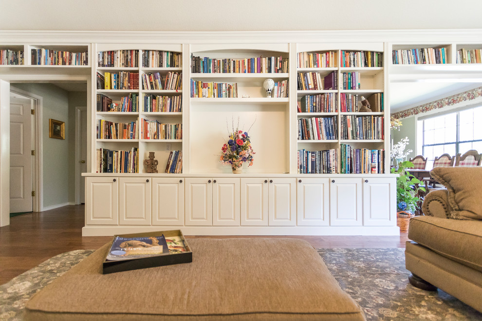 Foto de biblioteca en casa abierta clásica grande con paredes blancas, suelo laminado, pared multimedia y suelo marrón