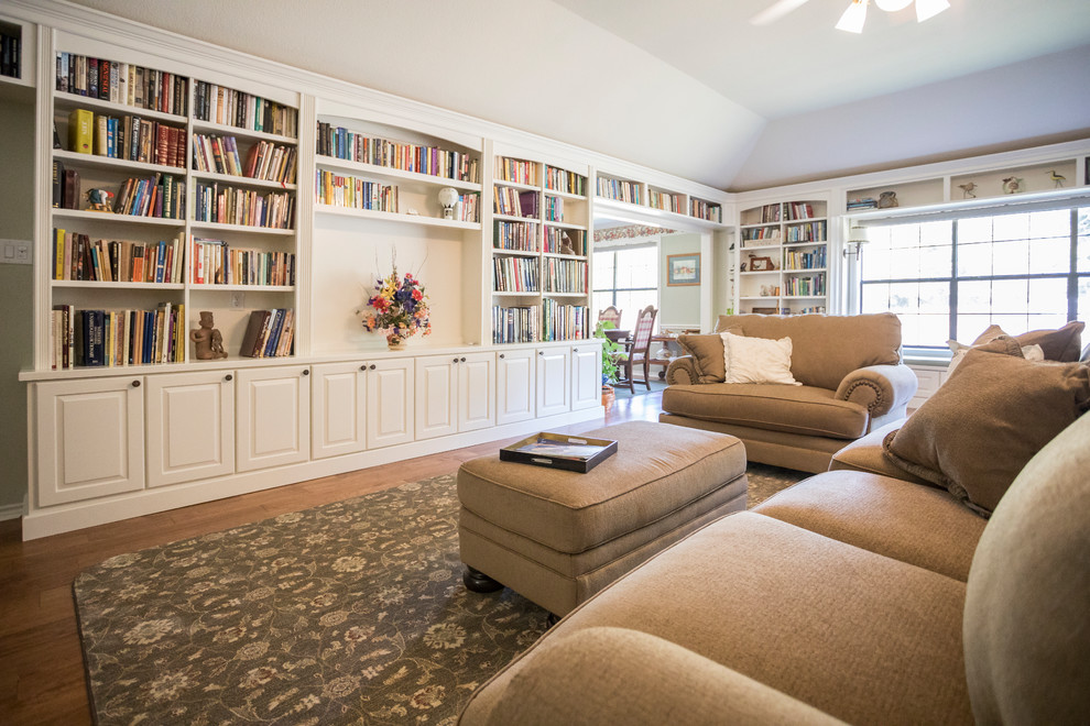 Exemple d'un grand salon chic ouvert avec une bibliothèque ou un coin lecture, un mur blanc, sol en stratifié, un téléviseur encastré et un sol marron.