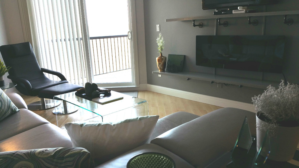 Foto de salón abierto moderno pequeño con paredes grises, suelo de madera clara, chimeneas suspendidas y televisor colgado en la pared