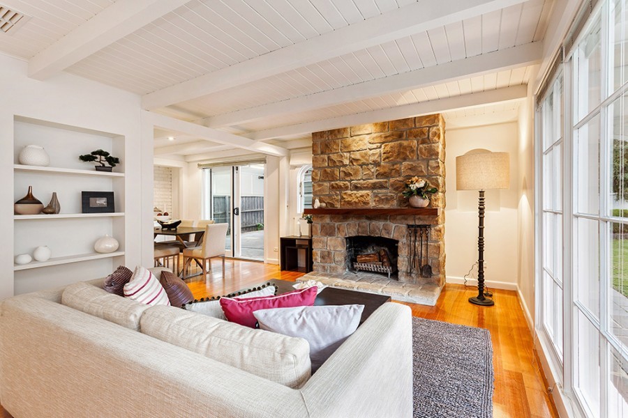 Photo of a modern formal enclosed living room in Melbourne with beige walls, medium hardwood flooring, a standard fireplace, a brick fireplace surround, a freestanding tv and brown floors.