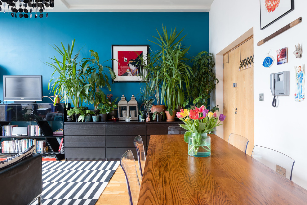 Offenes Eklektisches Wohnzimmer mit blauer Wandfarbe, hellem Holzboden, beigem Boden und freistehendem TV in London