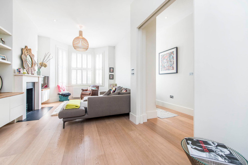 Offenes Modernes Wohnzimmer mit weißer Wandfarbe, braunem Holzboden, Kamin und braunem Boden in London