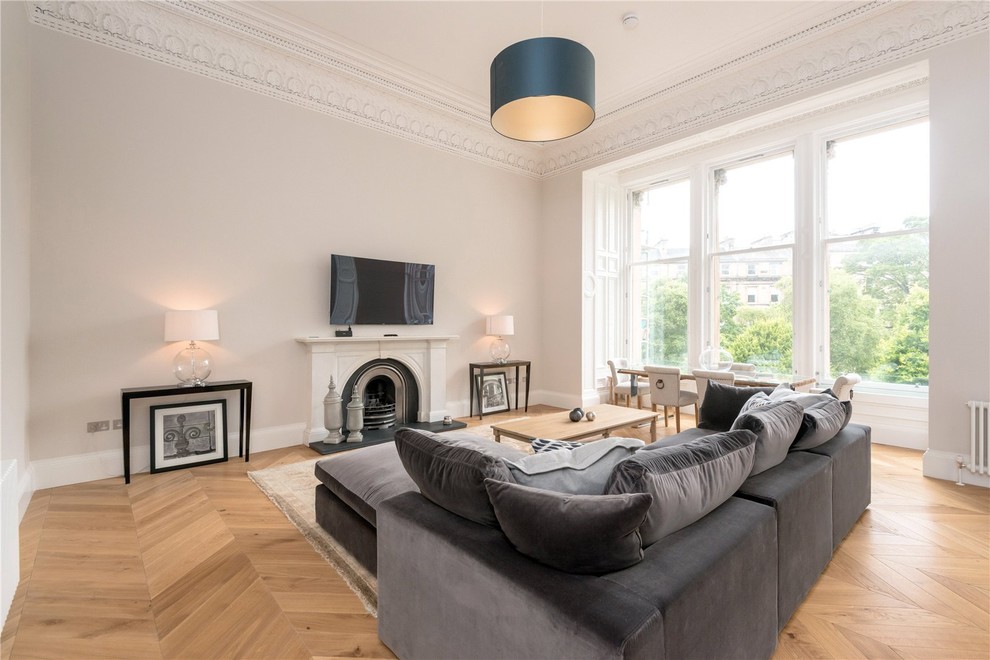Photo of a medium sized contemporary enclosed living room in Edinburgh with grey walls, light hardwood flooring, a standard fireplace, a wall mounted tv and beige floors.