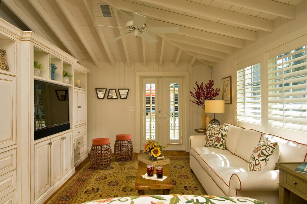 Example of a mid-sized beach style medium tone wood floor and brown floor living room design in Miami with white walls, no fireplace and a media wall