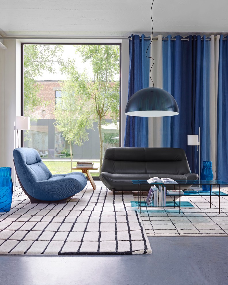 Immagine di un soggiorno minimalista di medie dimensioni e chiuso con pareti bianche, libreria e pavimento in cemento