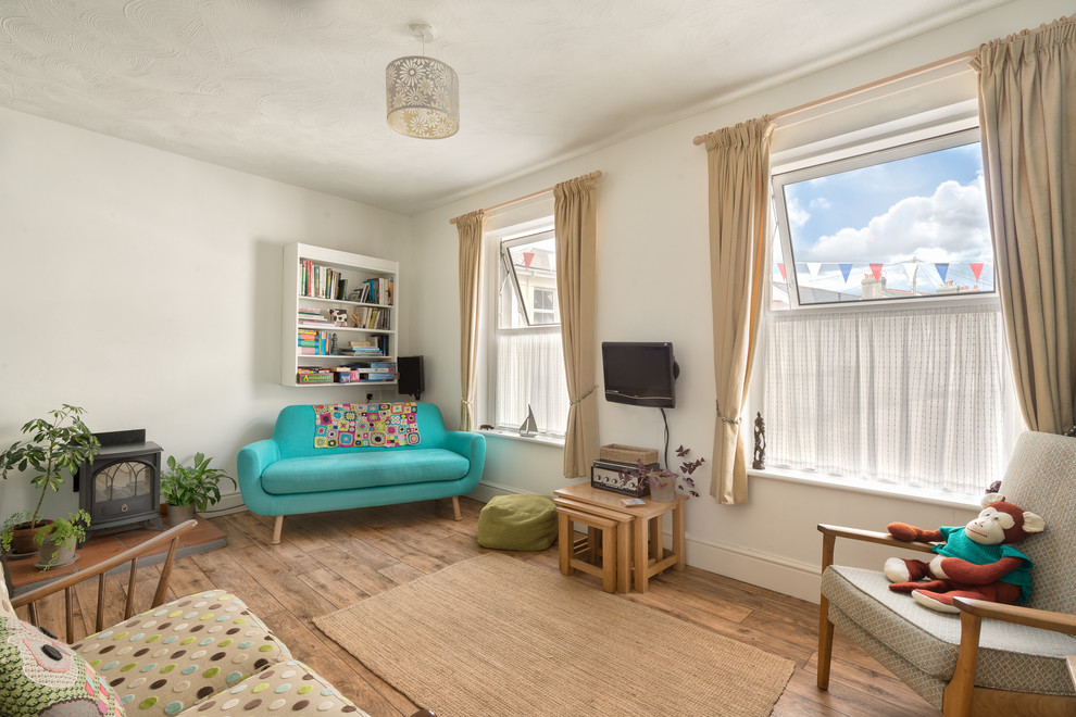 Foto di un piccolo soggiorno eclettico con pareti bianche, pavimento in legno massello medio e TV a parete