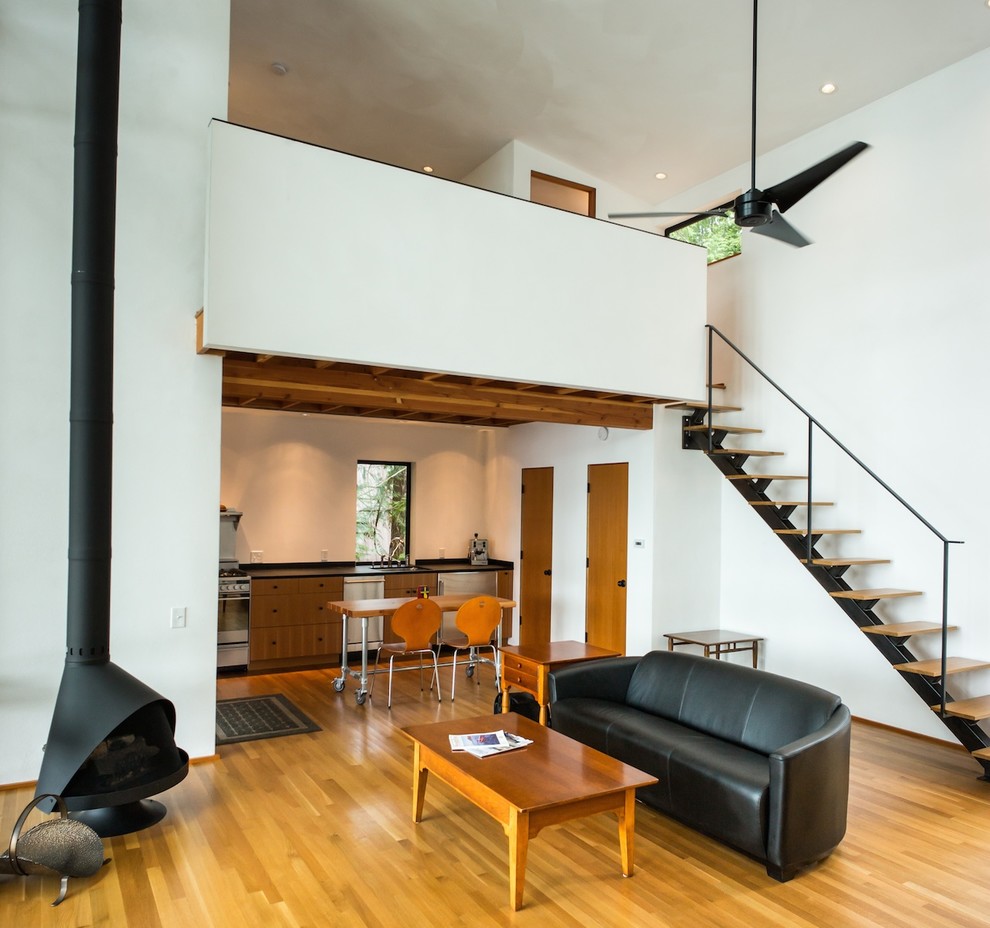 This is an example of a medium sized contemporary living room in Seattle with white walls, medium hardwood flooring, a wood burning stove and no tv.