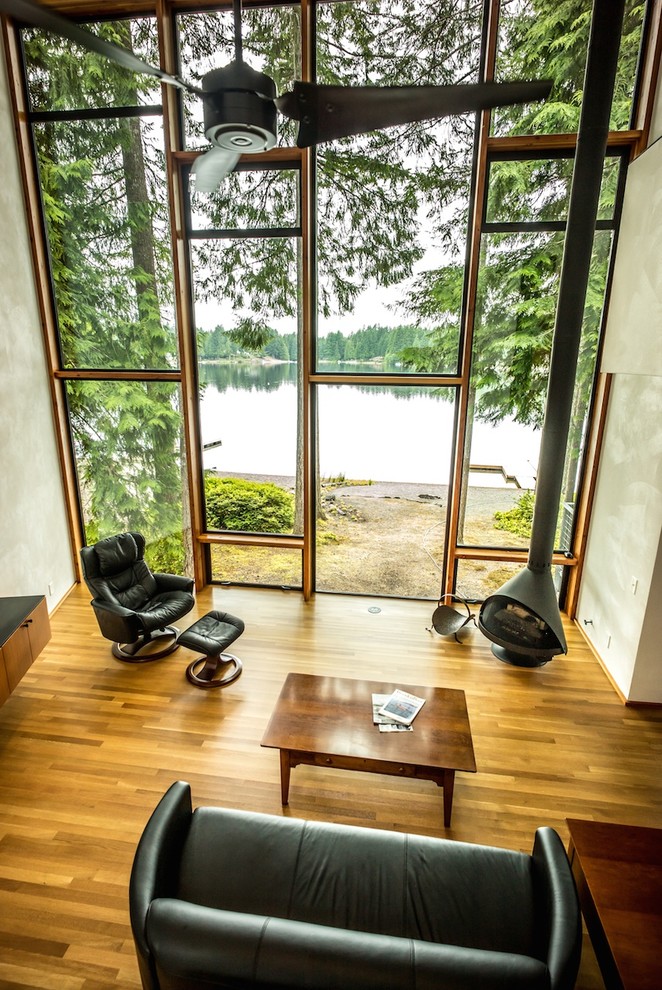 Modernes Wohnzimmer mit weißer Wandfarbe, braunem Holzboden und Kaminofen in Seattle