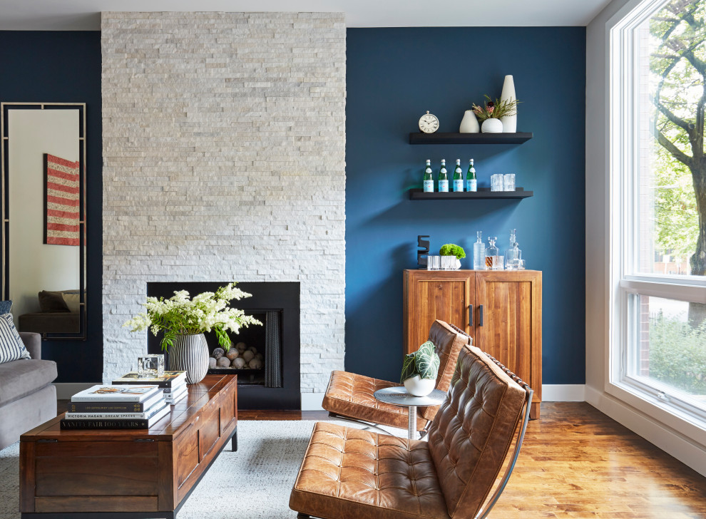 Стильный дизайн: парадная, изолированная гостиная комната среднего размера в стиле неоклассика (современная классика) с синими стенами, паркетным полом среднего тона, стандартным камином, фасадом камина из камня и коричневым полом без телевизора - последний тренд