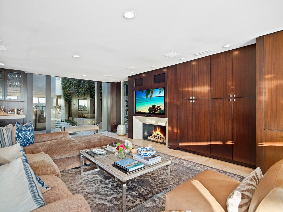This is an example of a world-inspired living room in Orange County with a home bar, a standard fireplace, a built-in media unit and beige floors.