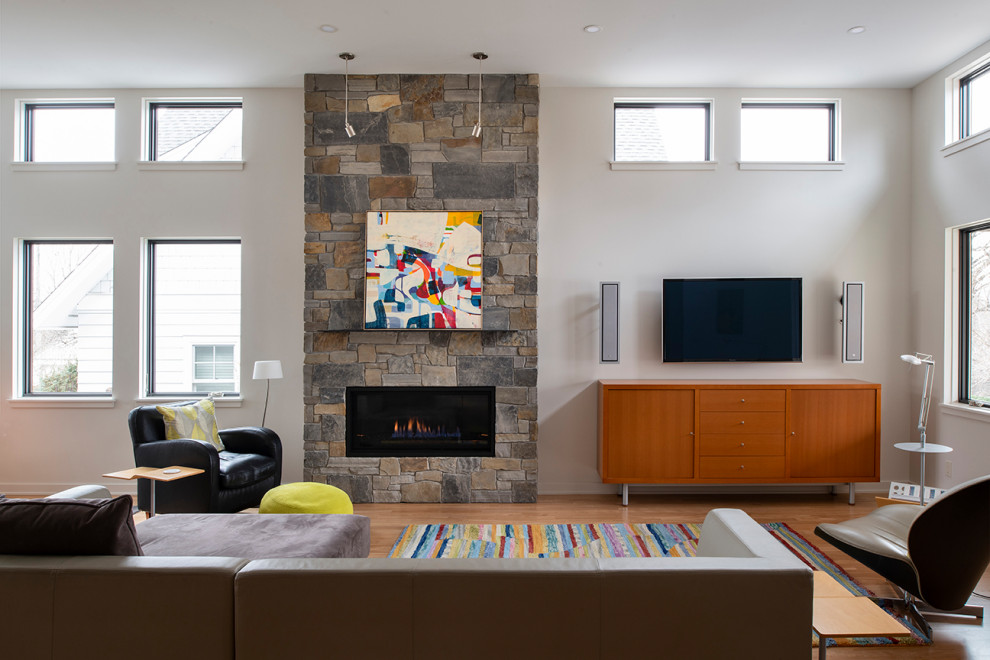 ミネアポリスにある中くらいなコンテンポラリースタイルのおしゃれなLDK (白い壁、無垢フローリング、標準型暖炉、石材の暖炉まわり、壁掛け型テレビ、茶色い床) の写真