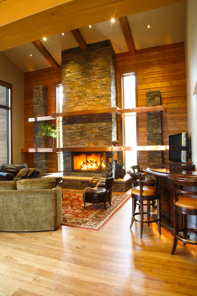 Example of a large arts and crafts formal and open concept medium tone wood floor living room design in Seattle with brown walls, a standard fireplace, a stone fireplace and a wall-mounted tv