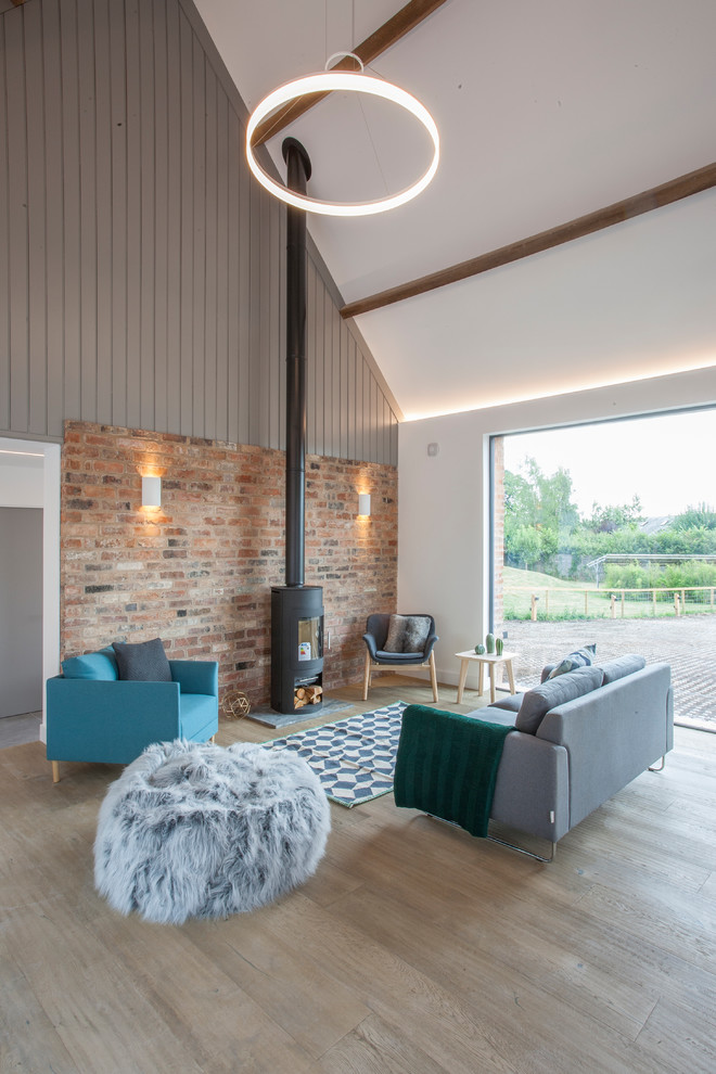 Idee per un soggiorno country aperto con pareti grigie, parquet chiaro, stufa a legna e pavimento beige