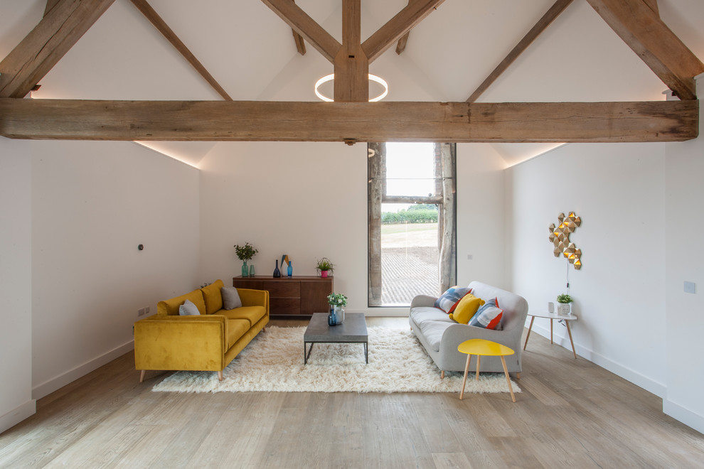 Farmhouse living room in West Midlands with white walls, light hardwood flooring and beige floors.