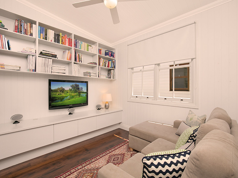 Cette image montre un salon traditionnel ouvert avec un mur blanc, parquet foncé, aucune cheminée et un téléviseur fixé au mur.