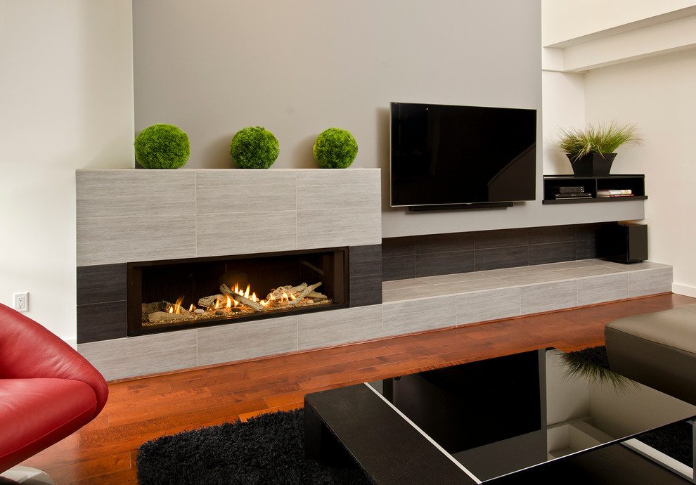 Modelo de salón moderno grande con paredes grises, suelo de madera oscura, chimenea lineal, marco de chimenea de baldosas y/o azulejos y televisor colgado en la pared