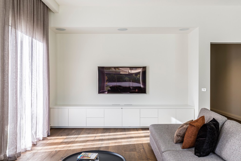 Esempio di un soggiorno minimal di medie dimensioni e aperto con pareti bianche, parquet scuro, nessun camino e TV a parete